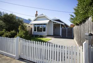 a white picket fence in front of a white house at GALWAY COTTAGE in Queenscliff