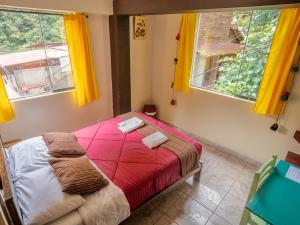 a bedroom with a bed with red sheets and two windows at ECO ART Best view Machu Picchu in Machu Picchu