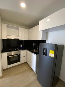 uma cozinha com um frigorífico preto e armários brancos em Elegancia y calidad el mejor sitio de la ciudad em Ibagué