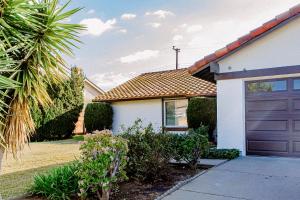 a white house with a brown garage door at Cozy Family Home - 20 Mins from Disneyland in Placentia