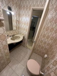 a bathroom with a toilet and a sink and a mirror at Quarto Aconchegante in Rio de Janeiro