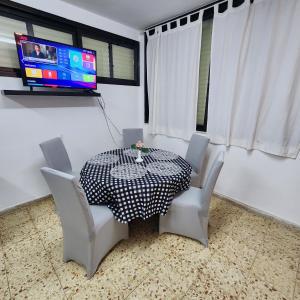 a dining room table and chairs with a tv on the wall at SEA VIEW ASHDOD in Ashdod