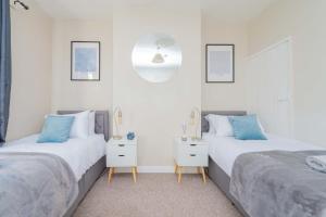 2 Betten in einem Zimmer mit weißen Wänden und blauen Kissen in der Unterkunft Central Townhouse Wolverhampton - Sleeps 8 - Ideal for Contractors & Families in Wolverhampton