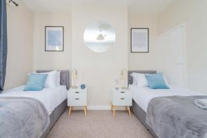 Cet hébergement comprend 2 lits dans une chambre dotée de murs blancs et d'oreillers bleus. dans l'établissement Central Townhouse Wolverhampton - Sleeps 8 - Ideal for Contractors & Families, à Wolverhampton