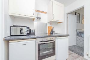 eine Küche mit weißen Schränken und einer Mikrowelle in der Unterkunft Central Townhouse Wolverhampton - Sleeps 8 - Ideal for Contractors & Families in Wolverhampton