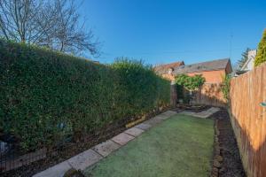 einen Hinterhof mit einem Zaun und einem Garten mit Gras in der Unterkunft Central Townhouse Wolverhampton - Sleeps 8 - Ideal for Contractors & Families in Wolverhampton