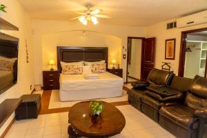 a bedroom with a bed and a couch and a table at Magnifica Villa Palmeras Pok ta Pok Zona Hotelera Cancun in Cancún