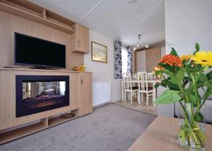 a living room with a television and a vase of flowers at Mercury Yacht Harbour And Holiday Park in Lower Swanwick