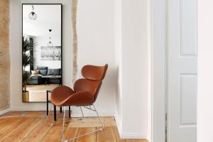 einen braunen Stuhl im Wohnzimmer mit Spiegel in der Unterkunft Be in Berlin Apartments im Bergmannkiez in Berlin