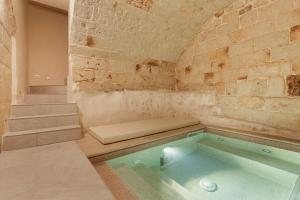 Cette chambre dispose d'un bain à remous et d'un mur en briques. dans l'établissement [Exclusive - Suite] SPA con Idromassaggio Jacuzzi, à Fasano