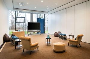 a living room with a flat screen tv and chairs at The Rilano Hotel München in Munich