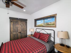 a bedroom with a bed with a checkered blanket and a window at Cliff's Edge. New Build, Breathtaking Views, Luxury Stay Near Zion in Orderville