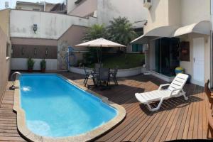 una piscina en una terraza con una silla y una sombrilla en Linda casa com piscina, en Balneário Camboriú