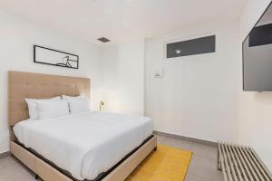 a white bedroom with a bed and a tv at Put On Your Red Shoes And At This Condo in Madiki +29 photos