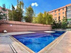 a swimming pool with blue water in front of a building at Superbe Appartement avec terrasse et jardin au cœur de l’hivernage in Marrakesh