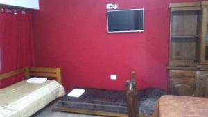 Habitación roja con 2 camas y TV en la pared. en Mi Lugar en Olavarría