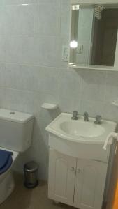 ein Badezimmer mit einem Waschbecken, einem WC und einem Spiegel in der Unterkunft Mi Lugar in Olavarría