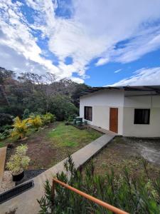 a house with a garden and a cloudy sky at Cabinas Selva Verde in Monteverde Costa Rica