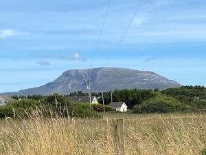 a mountain in the distance with houses in a field at Traditional 3-Bed Cottage sea mountain views in Falcarragh