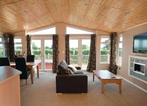 a living room with a couch and a tv at Athelington Hall Farm Lodges in Horham