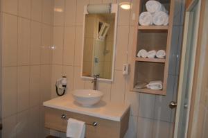 a bathroom with a sink and a mirror and towels at Kale Palace Hotel in Gokceada Town