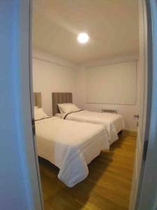 1 dormitorio con 2 camas con sábanas blancas en Departamento para vacaciones en Salta. en Salta