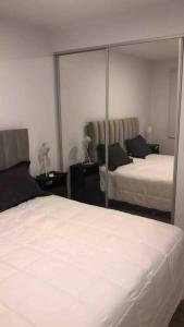 1 dormitorio con 2 camas y un espejo grande en Departamento para vacaciones en Salta. en Salta
