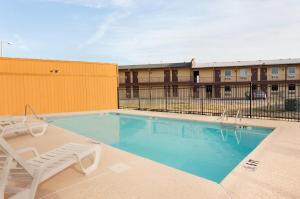 einen Pool mit einem Stuhl und einem Stuhl in der Unterkunft Super 8 by Wyndham Joplin in Joplin