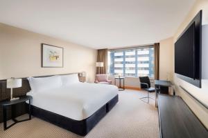 um quarto de hotel com uma cama grande e uma televisão de ecrã plano em JW Marriott Auckland em Auckland