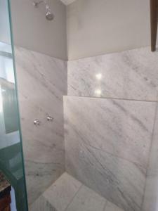 uma casa de banho com um grande chuveiro em mármore e uma porta de vidro. em Hotel Villa Salvador em Salvador