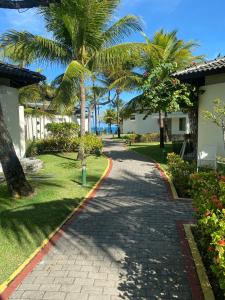 a cobblestone path in front of a resort with palm trees at Beach class Muro Alto 3202 in Porto De Galinhas