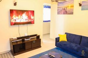 a living room with a blue couch and a tv at Neema Court Jamhuri-woodly in Nairobi