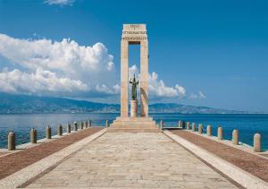 ein Denkmal auf einem Pier neben dem Wasser in der Unterkunft XENIA LUXURY ROOMS in Reggio di Calabria