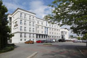 duży biały budynek z samochodami zaparkowanymi na parkingu w obiekcie Hotel Iskierka Business & Spa w Mielcu