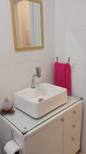 uma casa de banho com um lavatório branco e um espelho. em Apto novo com piscina e pátio na praia dos Ingleses em Florianópolis