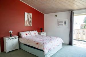 Schlafzimmer mit einem Bett mit roten Wänden und einem Fenster in der Unterkunft Jardine Lodge - Can sleep 22! in Corryong