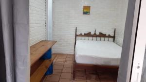 a small bedroom with a bed and a wooden table at Suíte a duas quadras da Praia e perto da Ilha do Mel in Pontal do Paraná