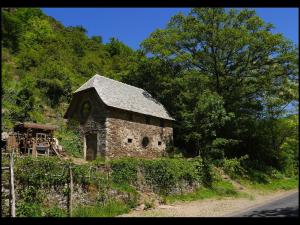 una vieja casa de piedra al lado de una carretera en Malrieu, en Le Fel