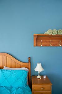 um quarto azul com uma cama e uma mesa com um candeeiro em Jardine Lodge - Can sleep 22! em Corryong