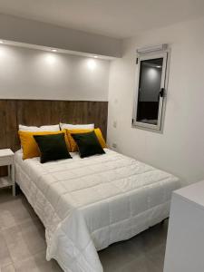 1 dormitorio con 1 cama blanca grande con almohadas amarillas en mini estudio en Villa La Angostura