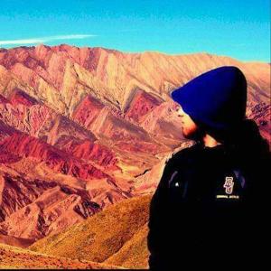 a person wearing a blue hat looking out over a mountain at Hostal familiar Hornocal in Humahuaca