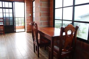 een houten tafel en stoelen in een kamer met ramen bij Hotel International in Pedernales