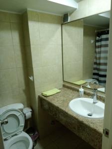 a bathroom with a sink and a toilet and a mirror at Amoblados MyK Portal Heroes in Iquique