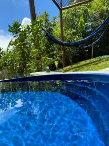 a blue swimming pool with a hammock in a yard at Sunshine Chalé Brasília-DF in Brasilia