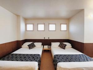 two beds in a room with three windows at Poly Hostel 2 Namba in Osaka