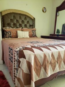a bedroom with a large bed with a brown and white comforter at #1 Jacaranda Vacation Home in Spanish Town