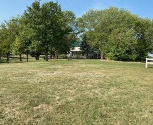 a field of grass with trees and a house at Mallory Estate in Chariton