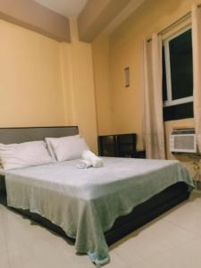 a bedroom with a bed with white sheets and a window at AAM Transient and Guest House in Manila