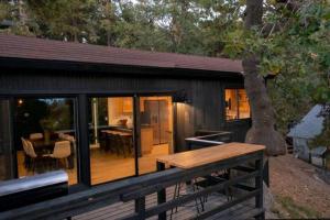 een kleine hut met een houten terras met een tafel bij Updated Mountain Cabin Retreat with 180 views off Deck and Balcony in Running Springs