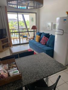 Flat Beach Class Resort Muro Alto في بورتو دي غالينهاس: غرفة معيشة مع أريكة زرقاء وطاولة